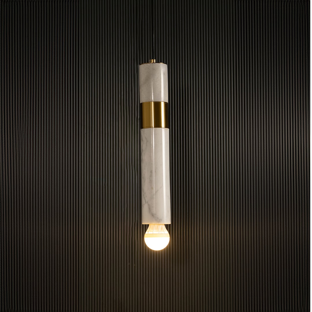 White marble and metal cylinder pendant light with exposed bulb hanging against dark textured wall with light on for elegant modern décor.