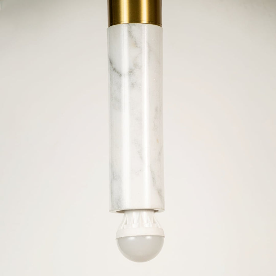 White marble and metal long cylinder pendant light with clear base shown in close up view with light off for elegant modern décor.