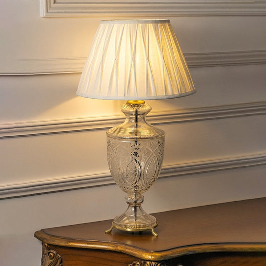 Clear etched glass table lamp with illuminated pleated fabric shade offering timeless elegance and warm interior lighting.