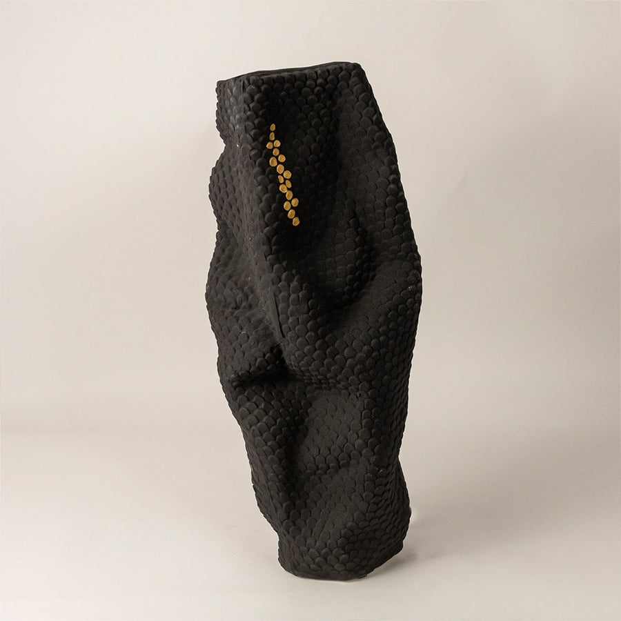 Matte black sculptural ceramic vase with gold accent dots on white background showcasing elegant handcrafted artistry.