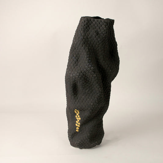 Black sculptural ceramic vase with abstract curved form and matte finish placed on white surface against neutral background showcasing modern artistic decor styling.