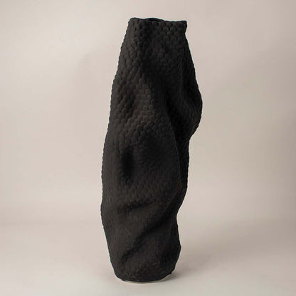 Sculptural black ceramic vase with detailed scale-like texture and organic design on clean white background for display.