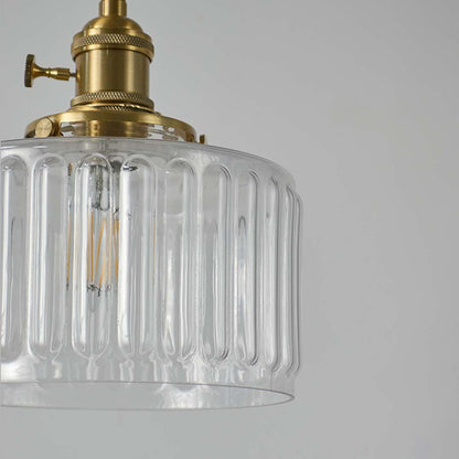 Closeup of ribbed clear glass and brass metal pendant light showcasing premium texture and craftsmanship.