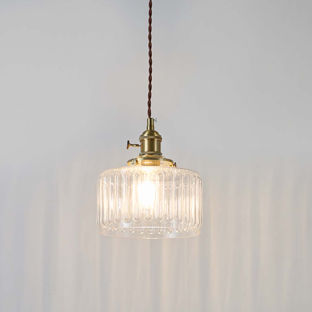Ribbed clear glass and brass metal pendant light with warm glow for elegant home decor spaces.