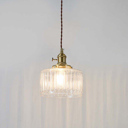 Ribbed clear glass and brass metal pendant light with warm glow for elegant home decor spaces.