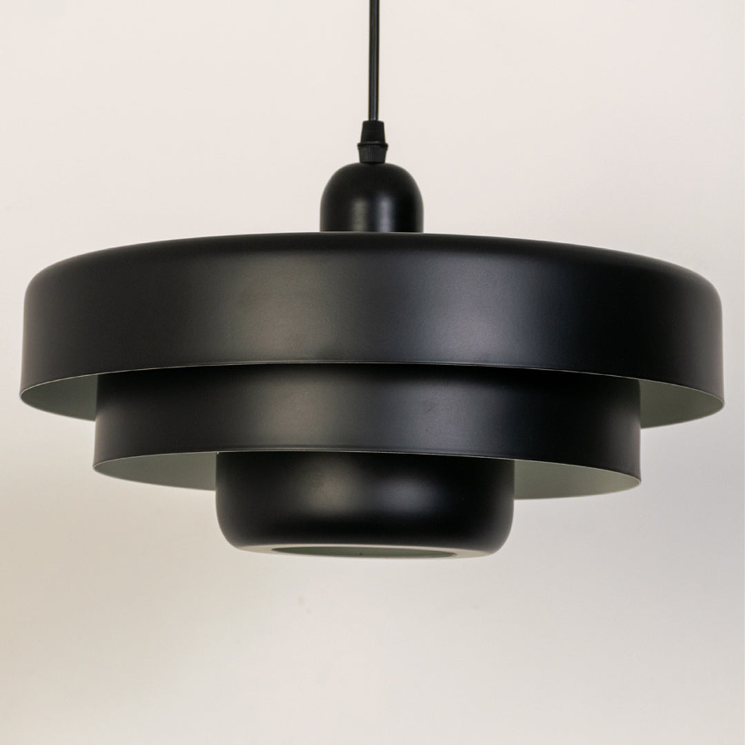 Closeup pendant light in black metal finish with layered shade design for kitchen or dining decor lighting white background.