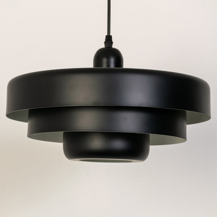 Closeup pendant light in black metal finish with layered shade design for kitchen or dining decor lighting white background.