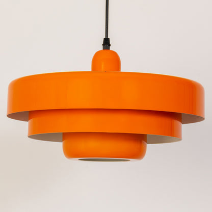 Closeup pendant light in orange metal finish with layered shade design for kitchen or dining decor lighting white background.