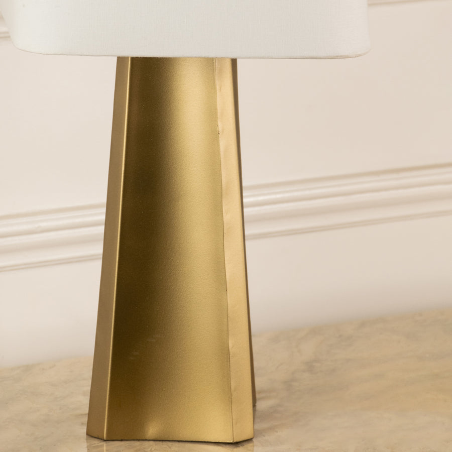 Closeup of gold metal table lamp base highlighting tapered design and premium finish for elegant bedroom or living room decor.