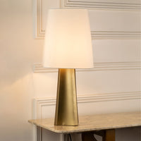 Brass metal table lamp with white fabric shade creating warm ambient lighting for sophisticated interior decor.