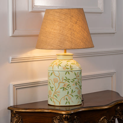 Table lamp with green patterned ceramic base and beige fabric shade for bedside or living room decor white background.