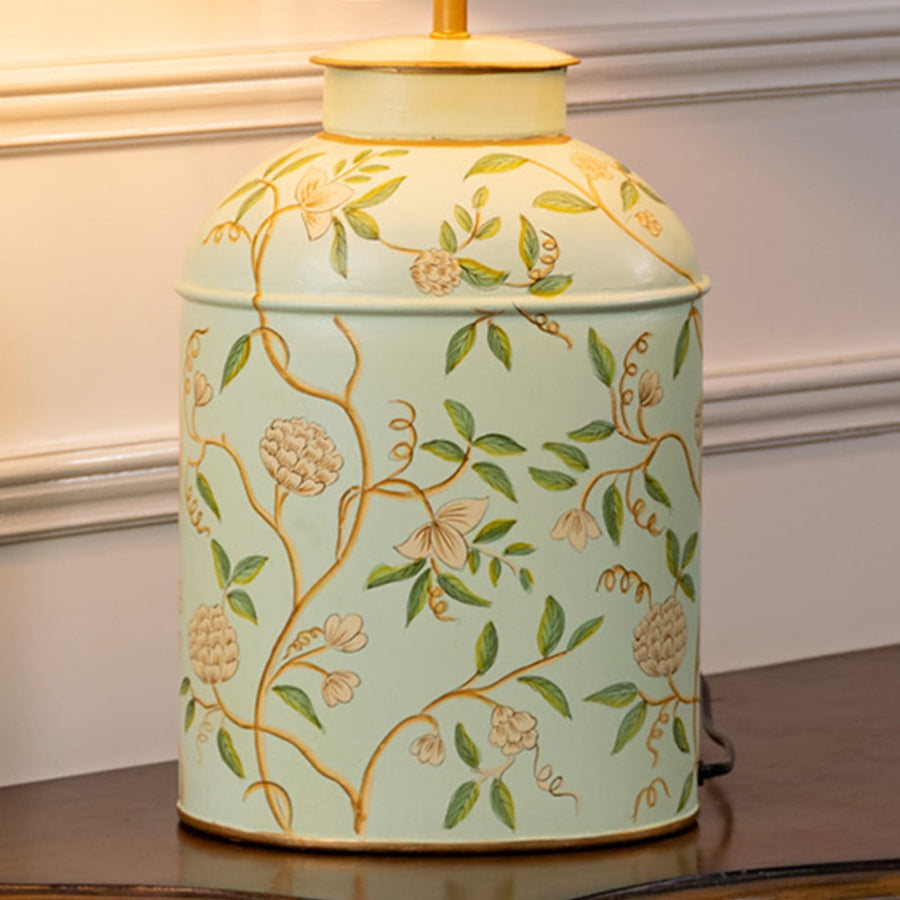 Table lamp closeup displaying light ceramic base with leafy floral detailing and matching fabric shade.