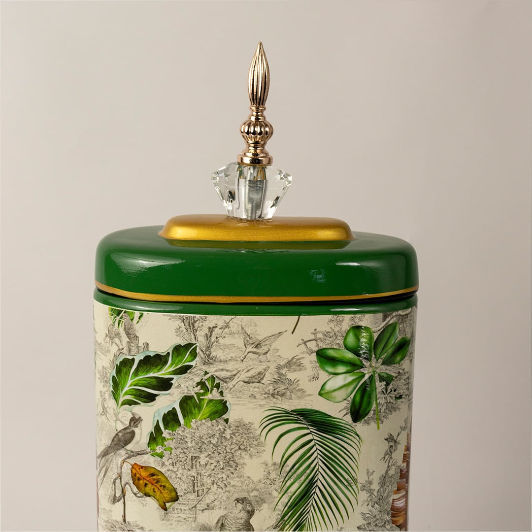 Closeup of tropical decorative jar showing detailed green leaves  gold rim  and crystal top finial.