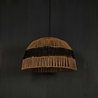 Handwoven jute pendant light with black stripe against dark background highlighting its raw natural texture and artisanal weave.