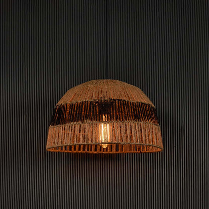 Stylish jute and black pendant light illuminated on dark background creating warm inviting glow through woven natural fibers.