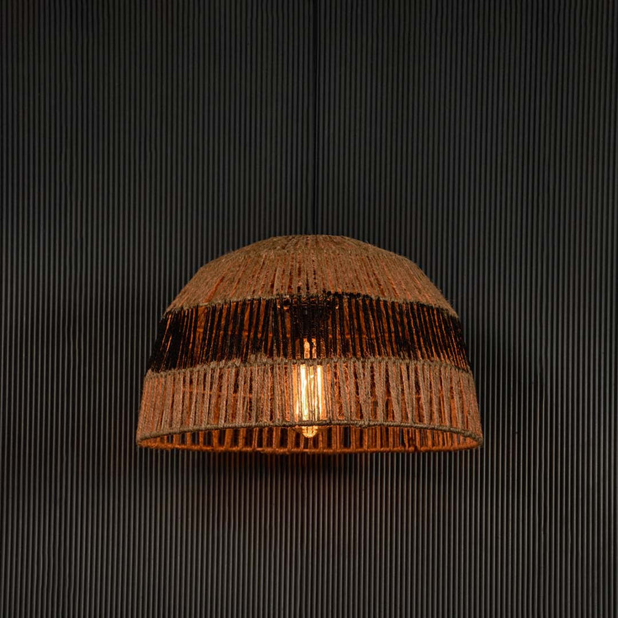 Stylish jute and black pendant light illuminated on dark background creating warm inviting glow through woven natural fibers.