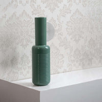 Green textured ceramic vase placed on a shelf for modern interior styling and elegant decorative home accents.