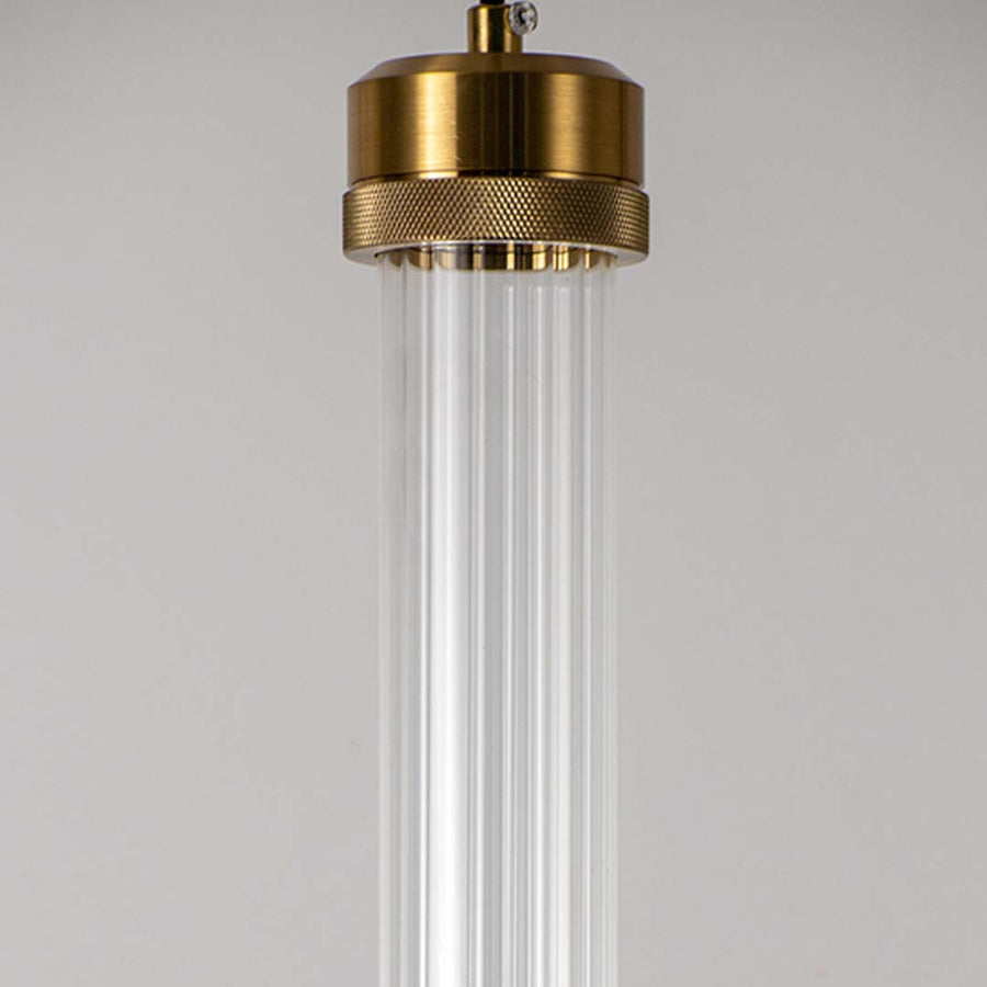 Closeup of clear glass tube pendant light with polished brass fittings highlighting elegant craftsmanship.