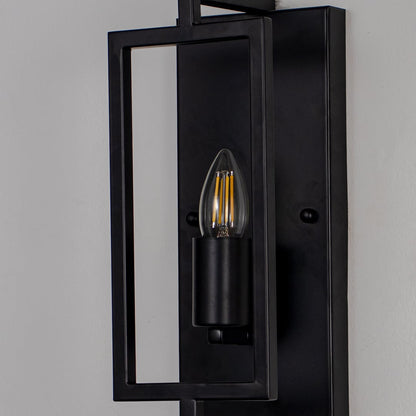 Closeup of wall lamp with sleek black rectangular metal frame and exposed bulb showcasing modern industrial design.