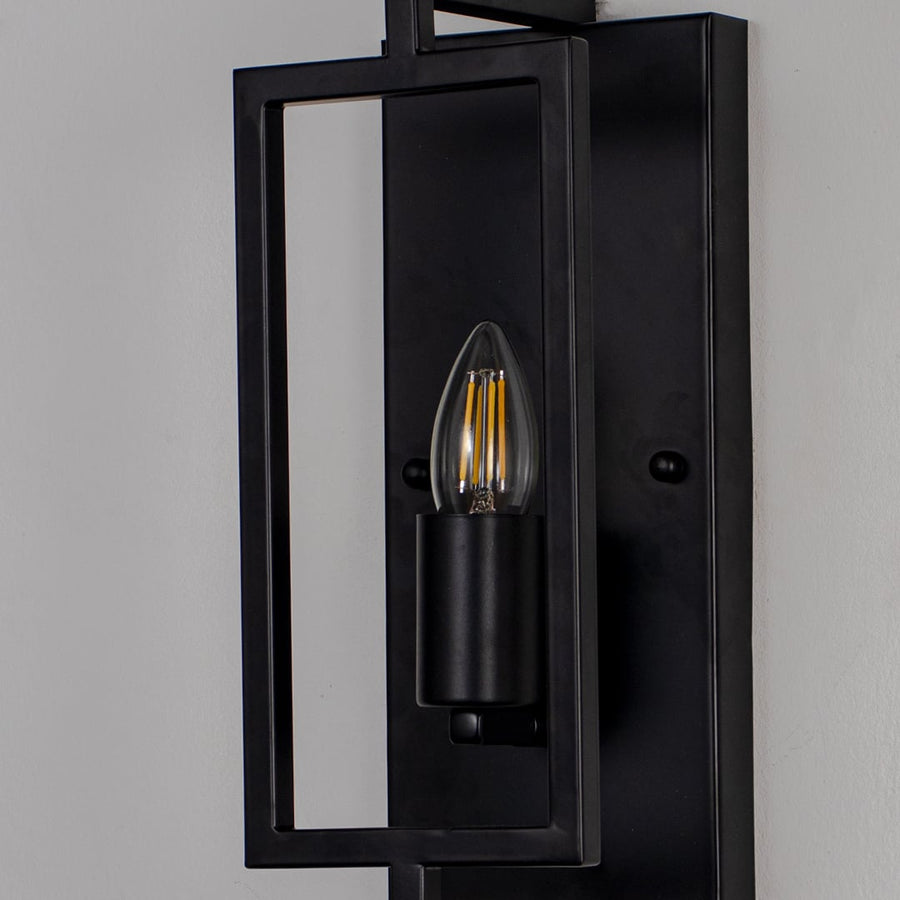 Closeup of wall lamp with sleek black rectangular metal frame and exposed bulb showcasing modern industrial design.