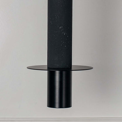 Black cylindrical pendant light with flat disc detail and matte finish hanging against neutral wall background highlighting sleek modern minimal lighting design.