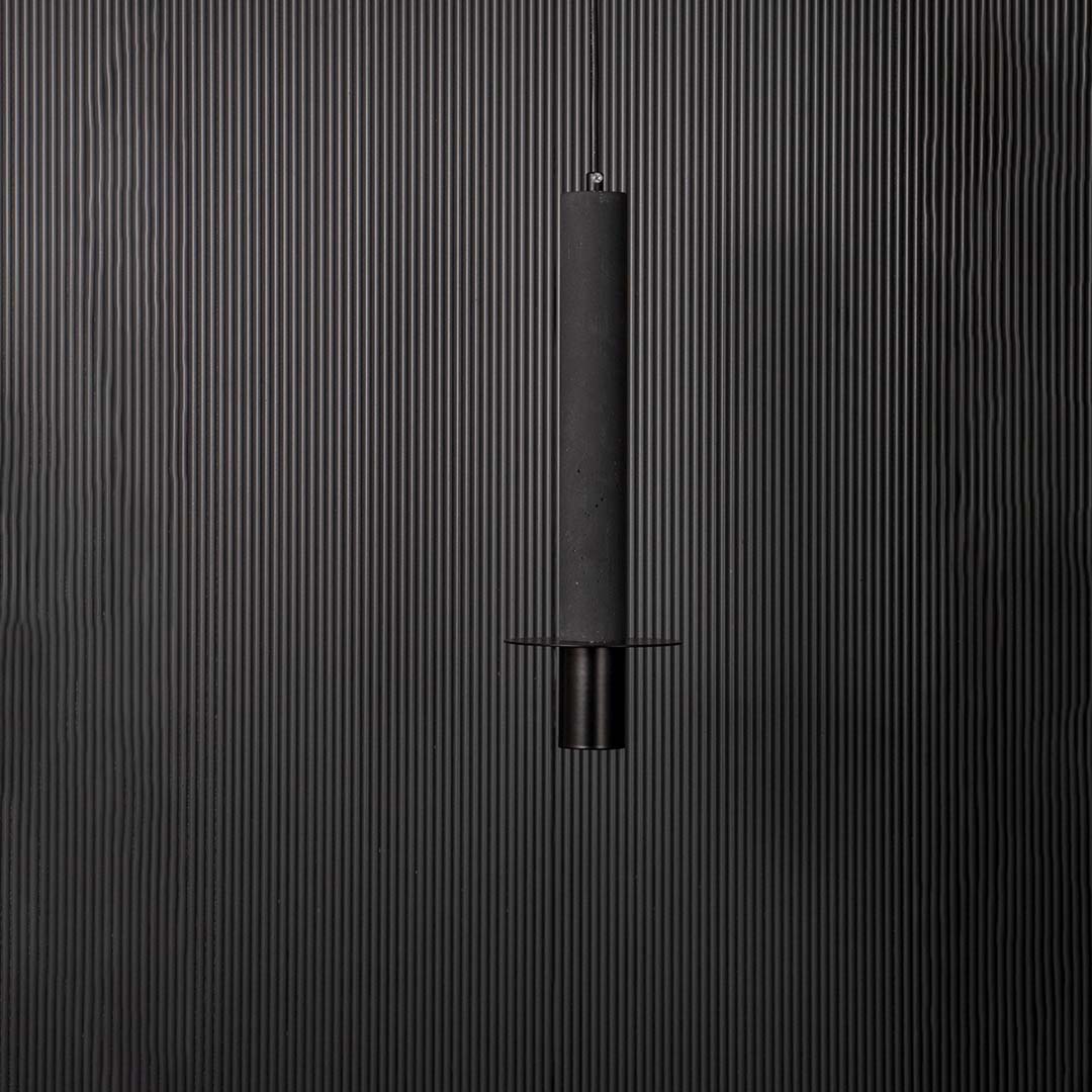 Closeup of slim black cylindrical pendant ceiling light showing fine details and modern minimalist hanging design style.