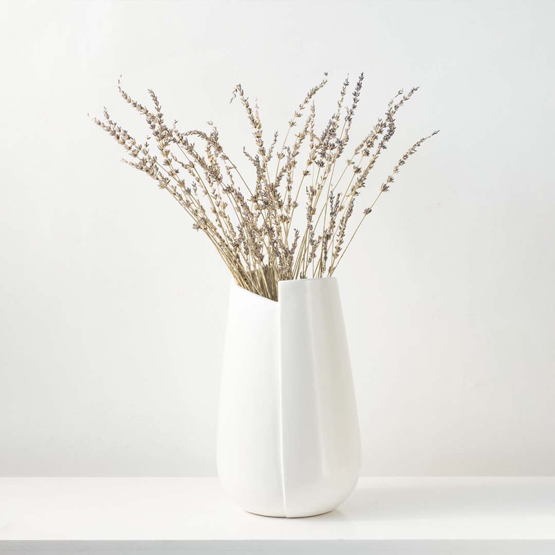 Minimal white ceramic vase placed on a clean pedestal in a bright modern setting  adding a soft contemporary touch to the lifestyle space.