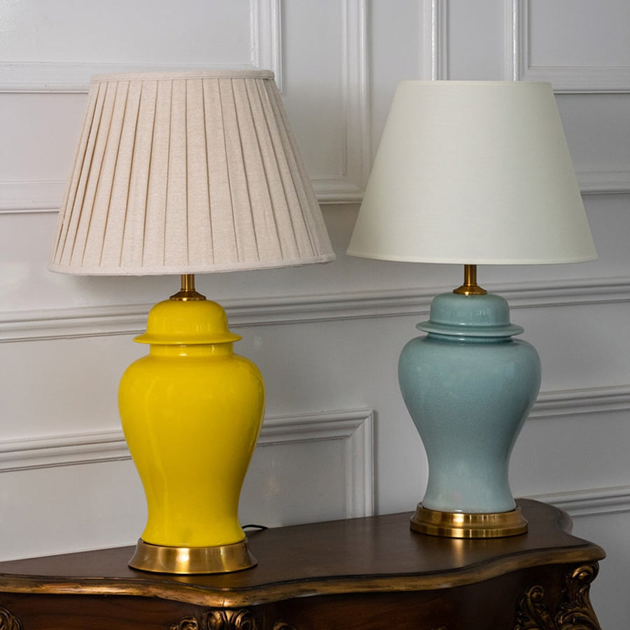Stylish yellow ceramic table lamps with golden base and pleated fabric shades displayed in grouped view.