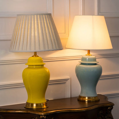 Set of yellow ceramic table lamps with golden base and pleated shades glowing in lifestyle views.