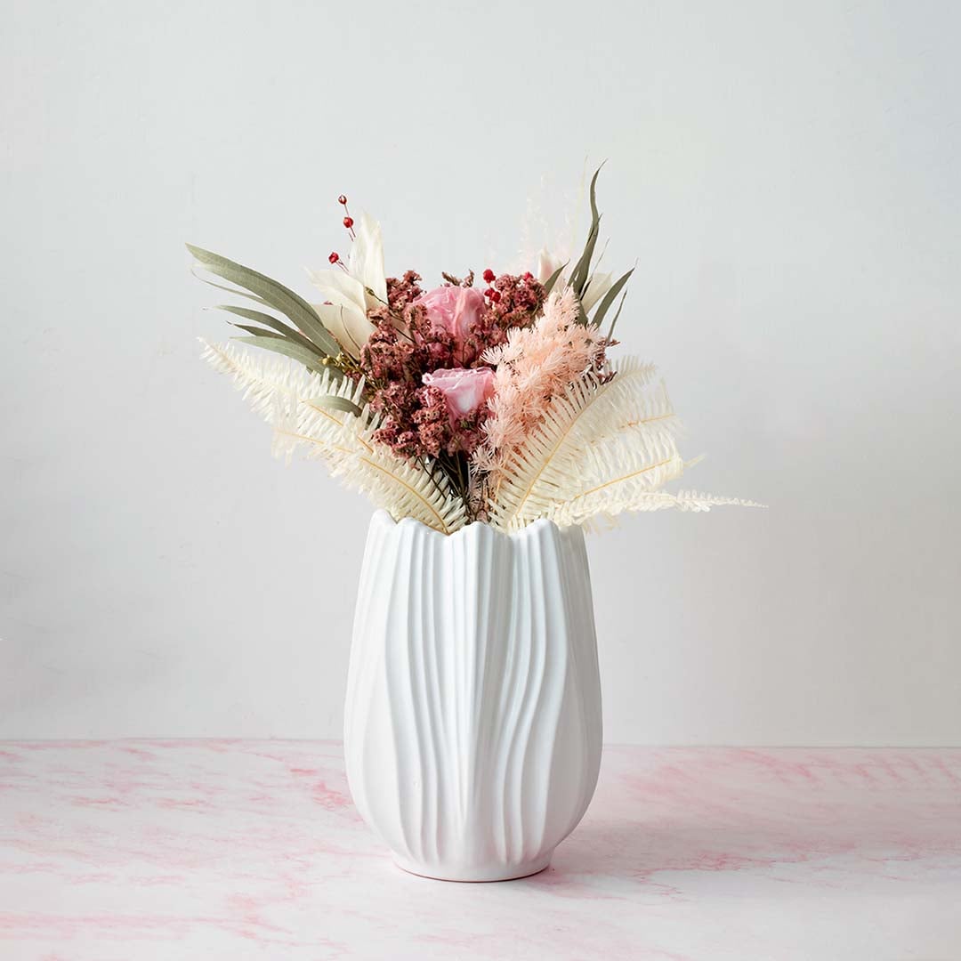 Stylish white textured vase placed on a pink marble surface with pastel flowers ideal for modern decor.