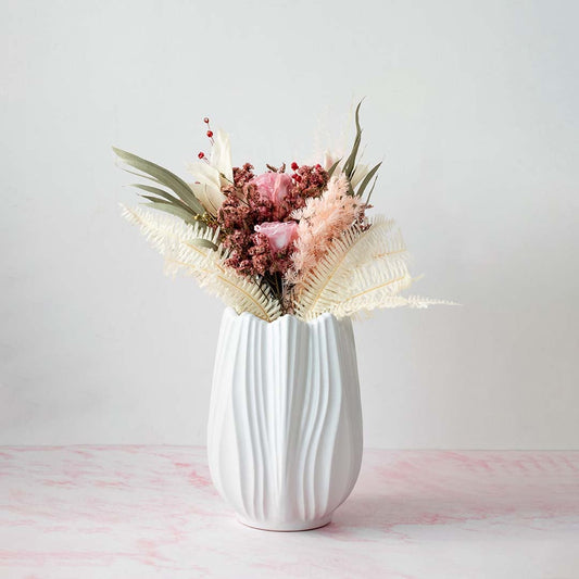 Stylish white textured vase placed on a pink marble surface with pastel flowers ideal for modern decor.