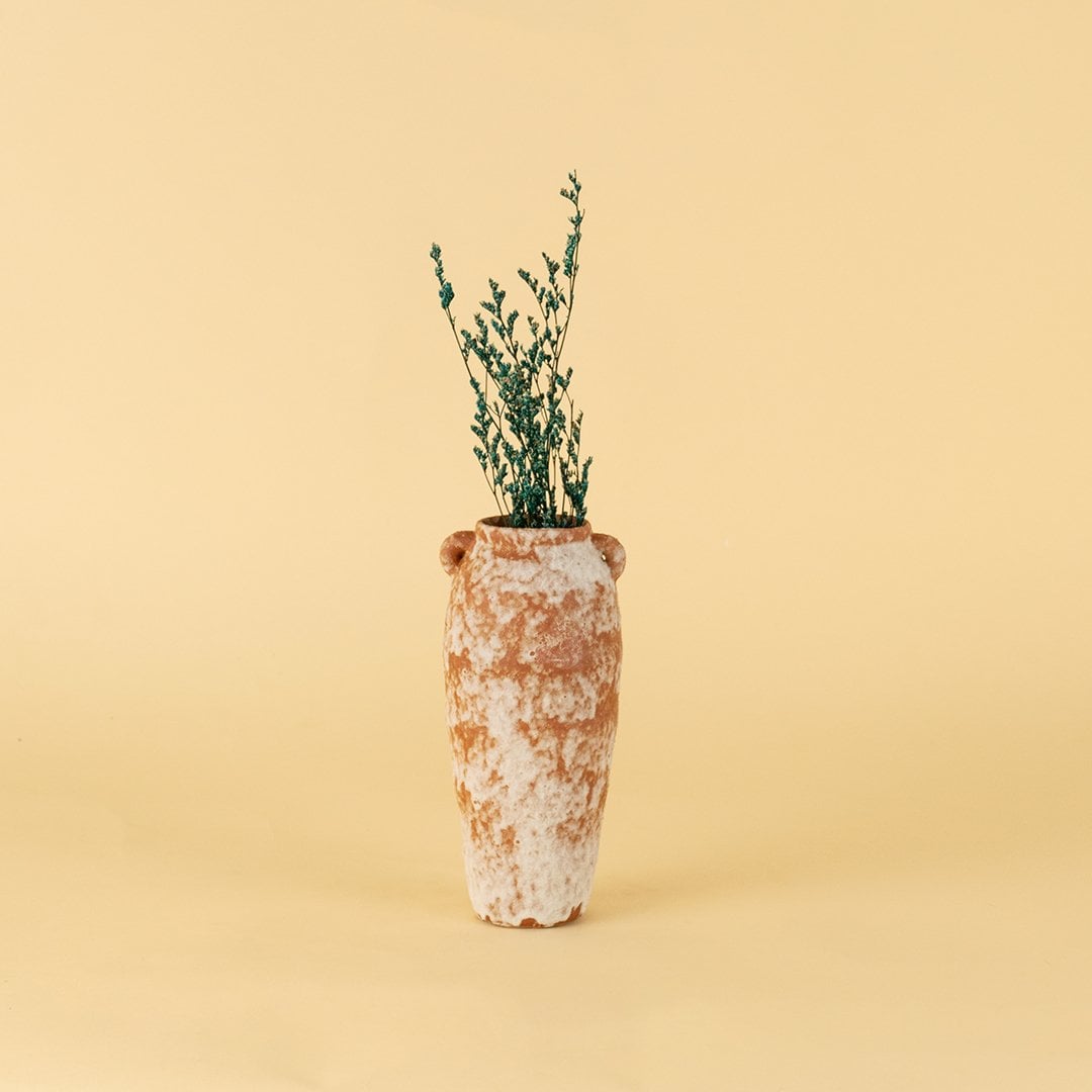 Rustic terracotta ceramic vase styled with greenery on wooden table against neutral wall for warm minimal interiors.