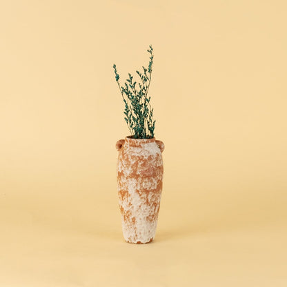 Rustic terracotta ceramic vase styled with greenery on wooden table against neutral wall for warm minimal interiors.