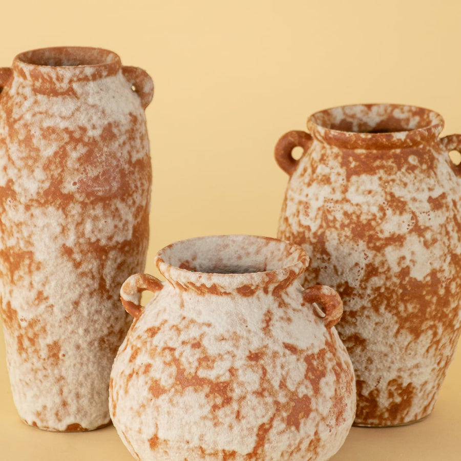 Set of rustic terracotta ceramic vases with unique shapes and dual handles in earthy finish for tabletop decoration.