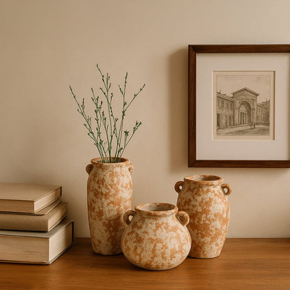 Handcrafted terracotta ceramic vase in rustic brown white finish styled on wooden table with books and wall art decor.