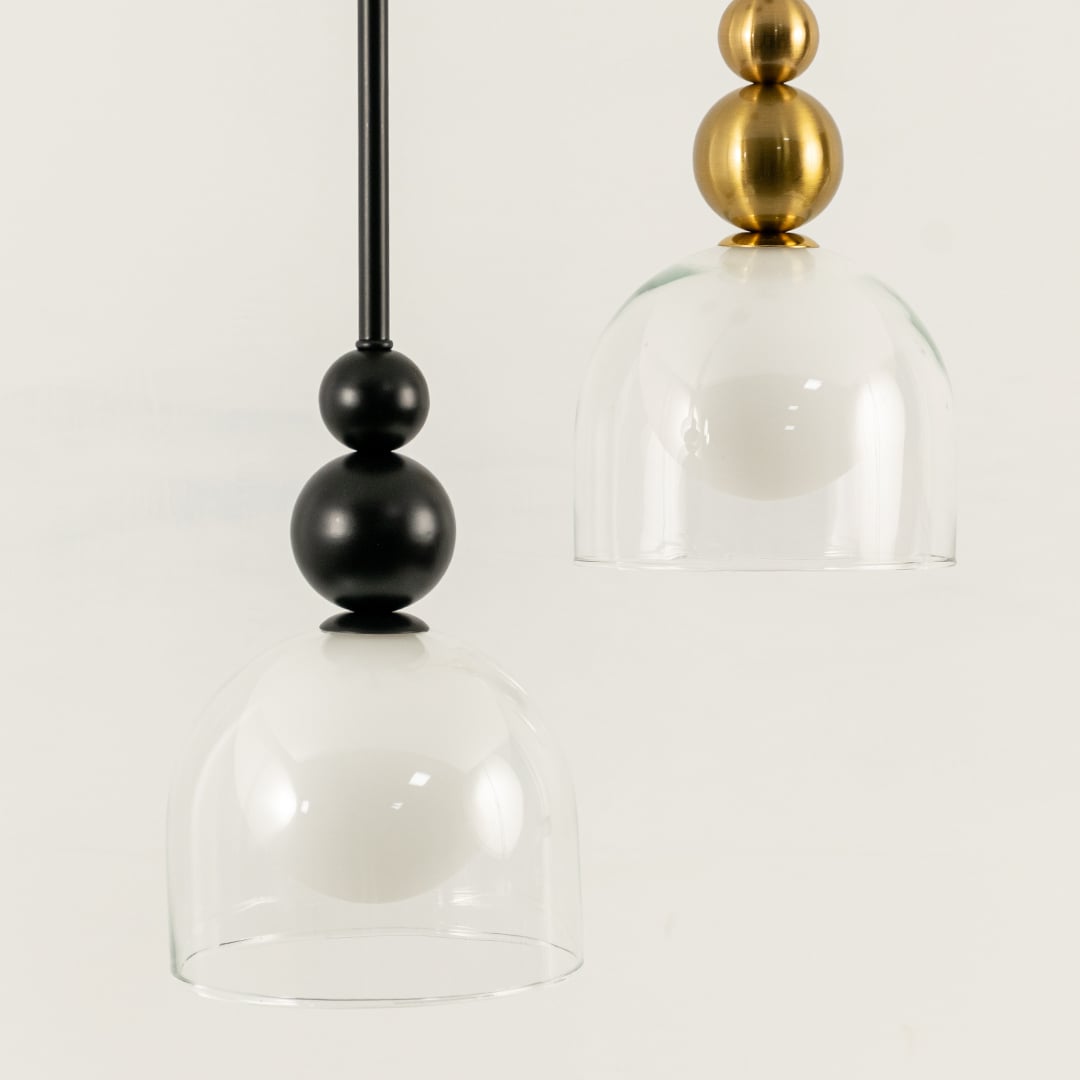 A pendant pair with black fittings and white globes enclosed in clear glass shades ideal for modern LED lighting and minimal interior décor styling.