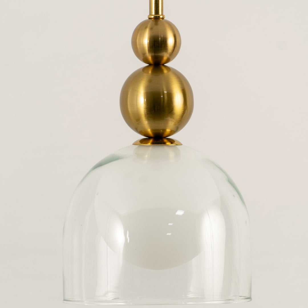 Closeup of gold metal pendant light with clear glass shade for elegant dining room and kitchen decor styling.