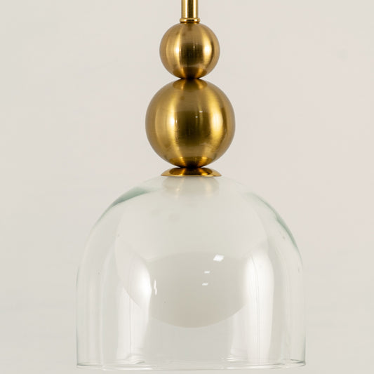 Closeup of gold metal pendant light with clear glass shade for elegant dining room and kitchen decor styling.