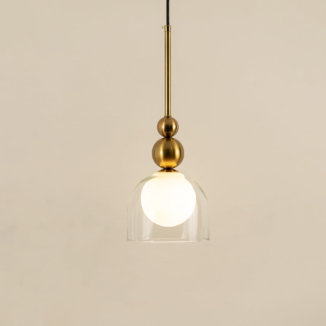 Gold metal pendant light with frosted glass globe illuminated to display luxury modern decorative ceiling lighting.