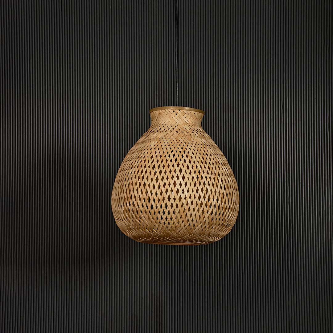 Woven rattan pendant light with bulbous handcrafted shade shown off on black background for rustic home decor.