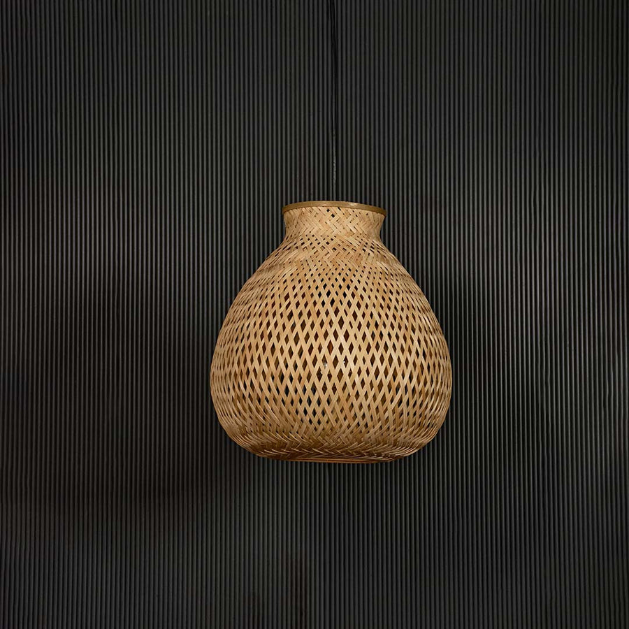 Woven rattan pendant light with bulbous handcrafted shade shown off on black background for rustic home decor.