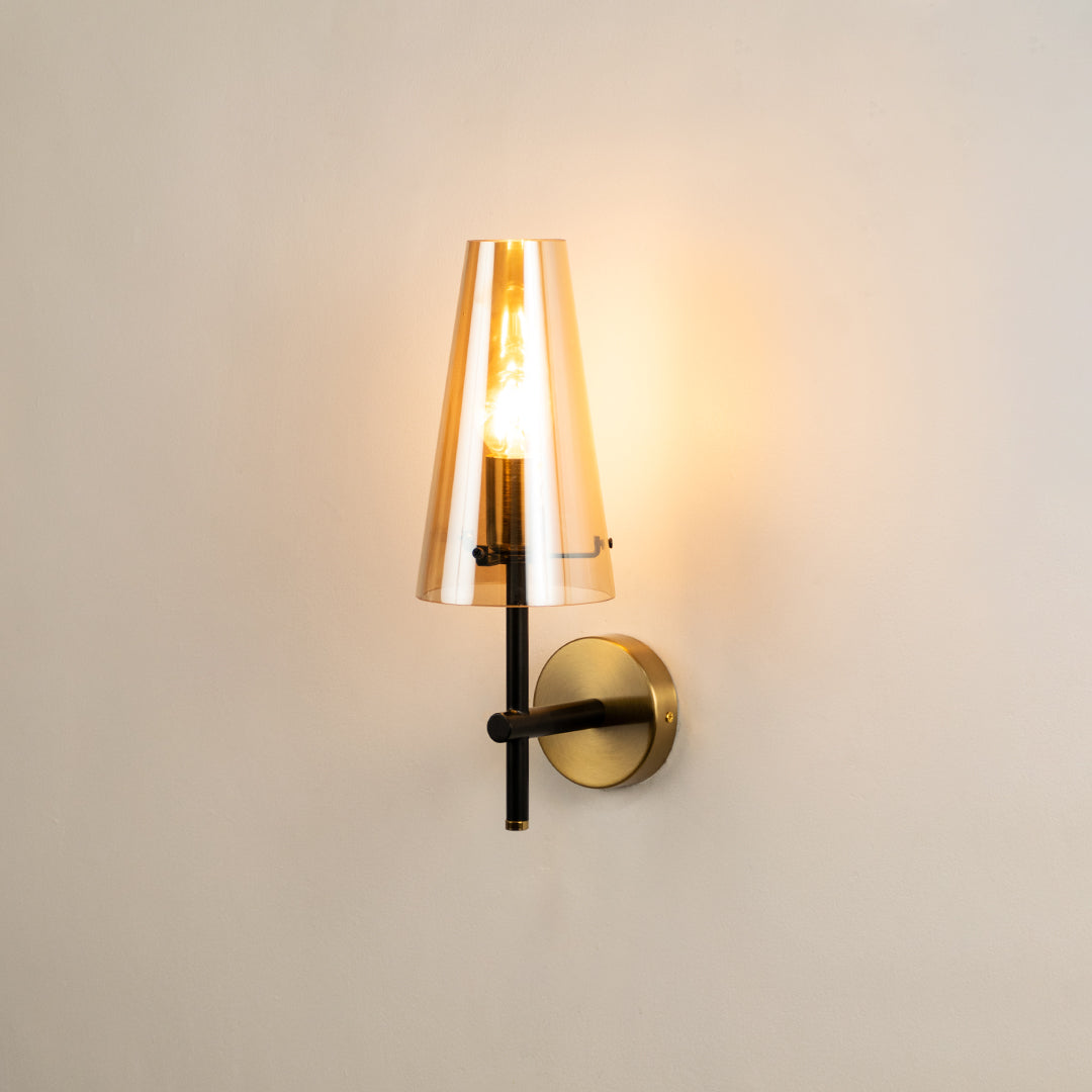 Modern brass wall light with cone glass shade creating warm elegant interior lighting ambiance.