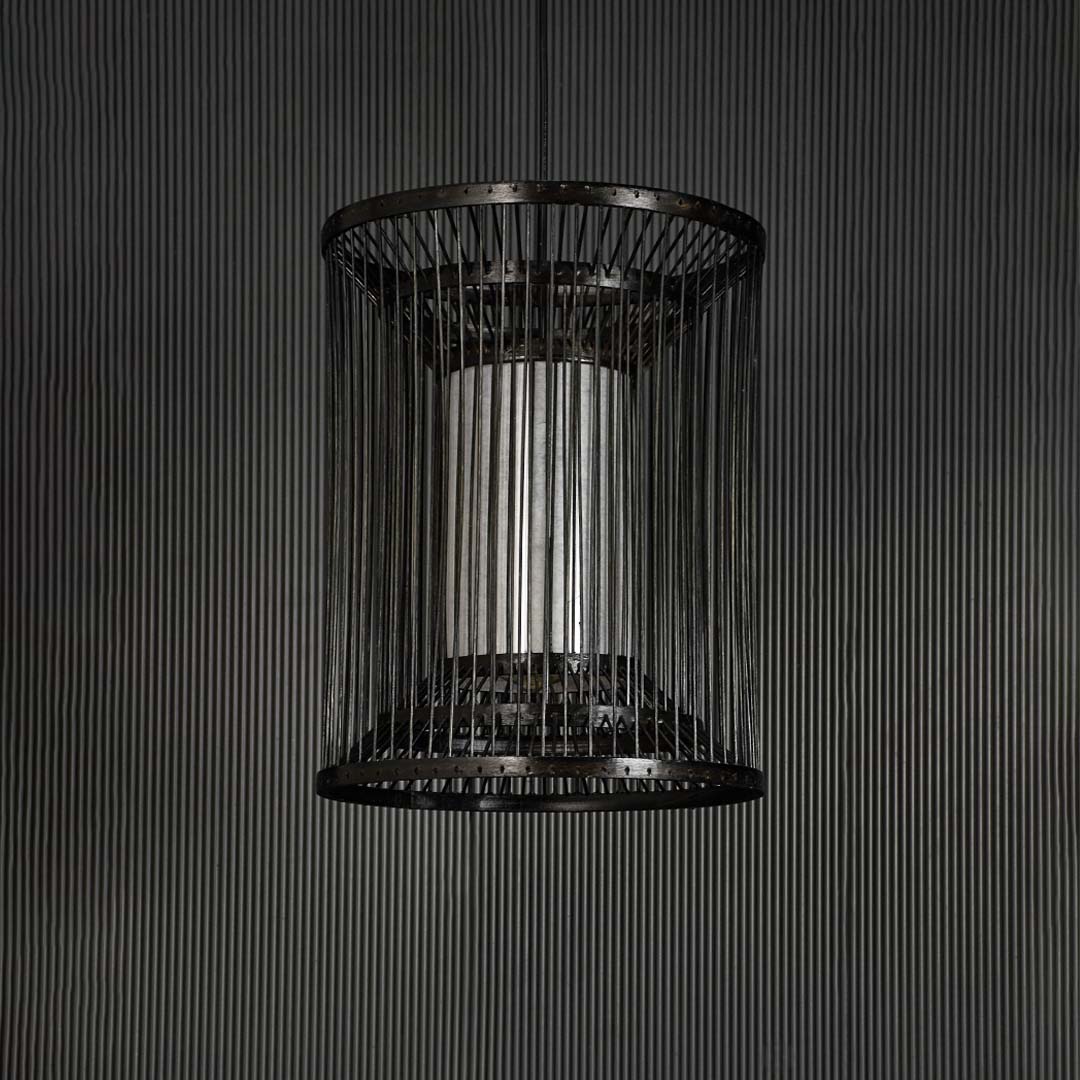 Black wire pendant light on dark background highlighting its minimalist silhouette and detailed metalwork.