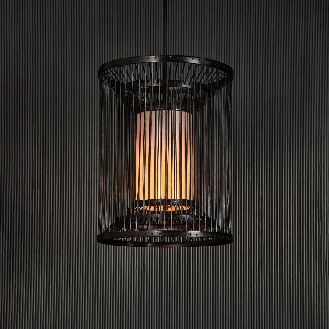 Black wire pendant light glowing warmly against black background revealing modern elegance and geometric charm.