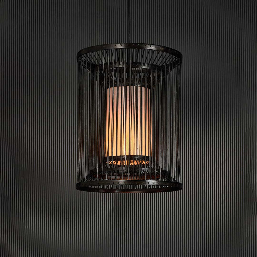 Black wire pendant light glowing warmly against black background revealing modern elegance and geometric charm.