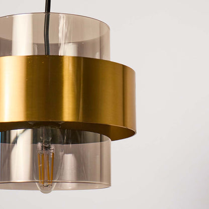 Closeup of gold and glass pendant light highlighting sleek cylindrical design and fine reflective finish for modern decor.