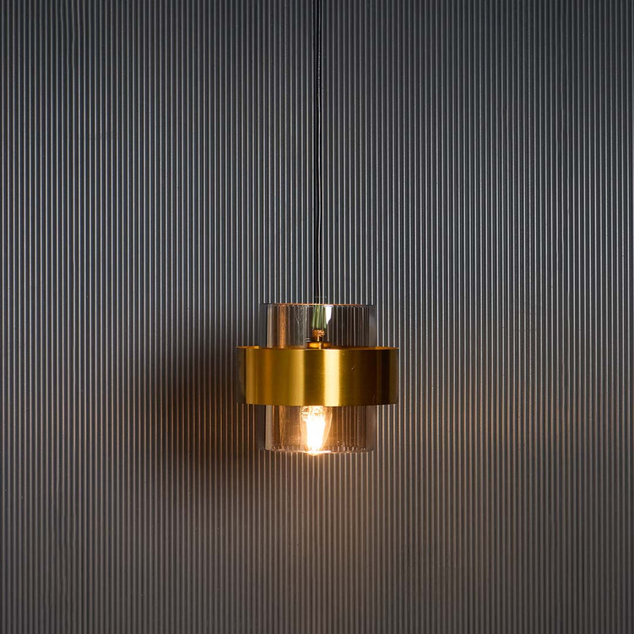 Gold glass pendant light glowing warmly against black background creating elegant contrast for premium home interiors.