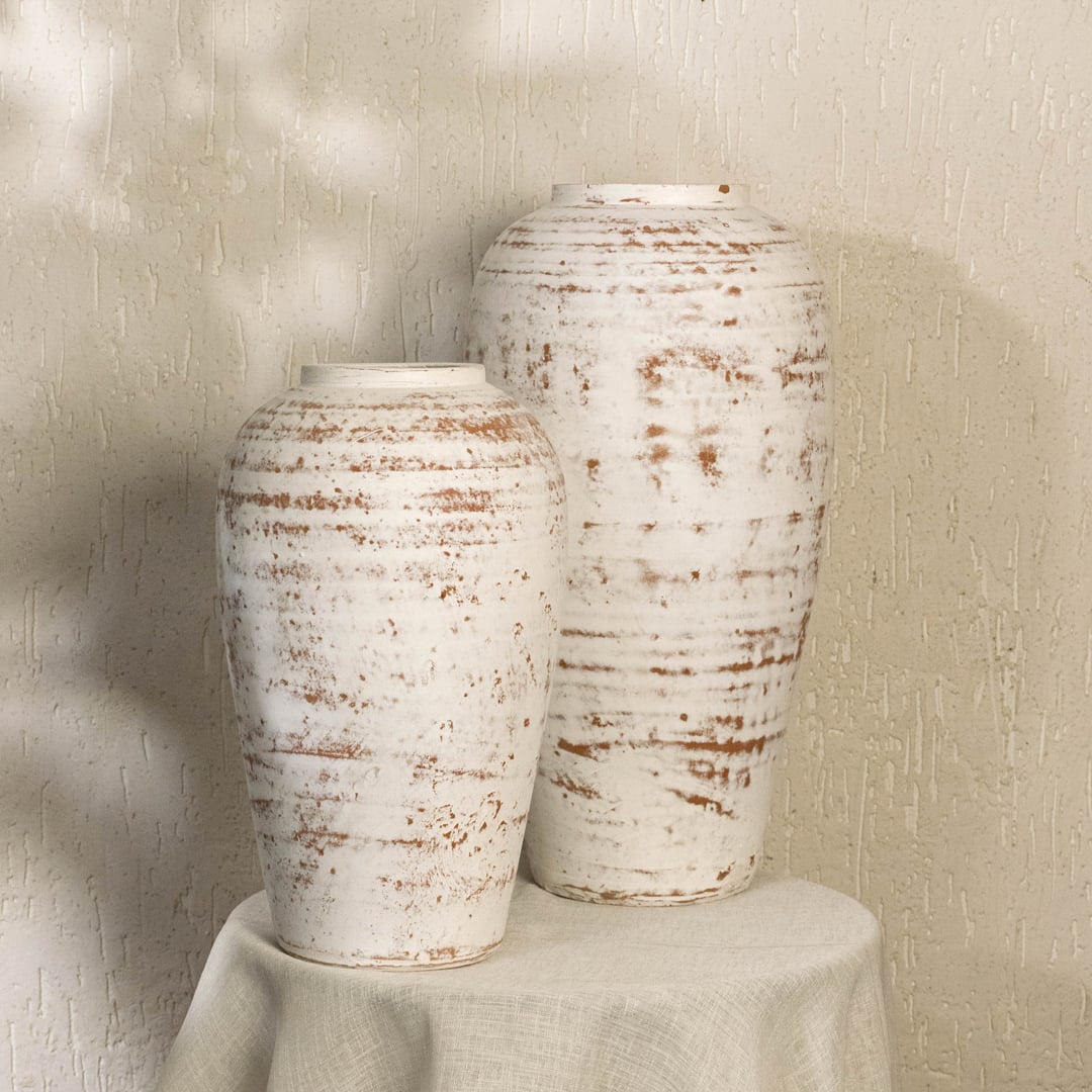 White rustic tall decorative vase arranged with matching decor pieces creating a stylish grouped display for warm contemporary interior settings.