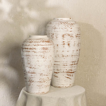 White rustic tall decorative vase arranged with matching decor pieces creating a stylish grouped display for warm contemporary interior settings.