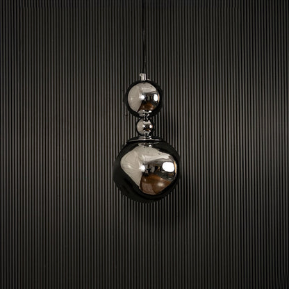 Reflective chrome pendant light with silver finish displayed on dark background with lights off highlighting texture.